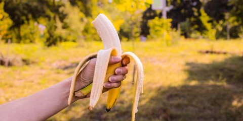 Hand holding peeled banana in a forest