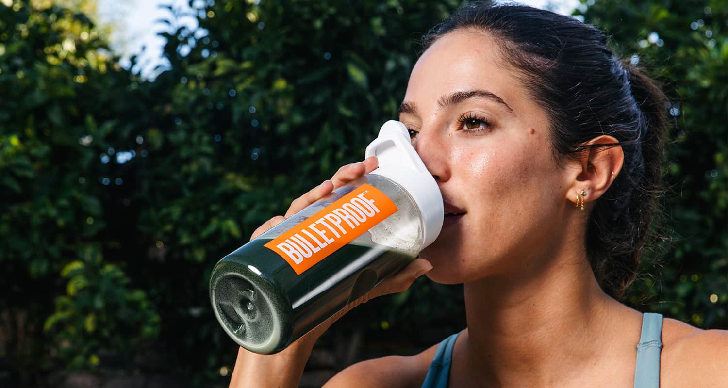 woman drinking greens drink during a workout