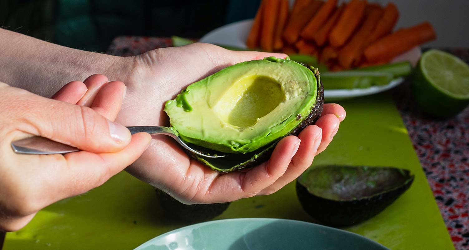 hand scooping an avocado