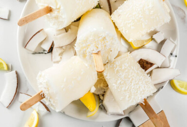 Dish of bulletproof lemon ginger coconut popsicles with ingredients scattered about