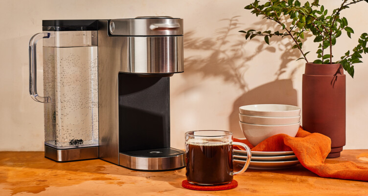 coffee machine with a fresh cup of coffee in a clear mug in front of it