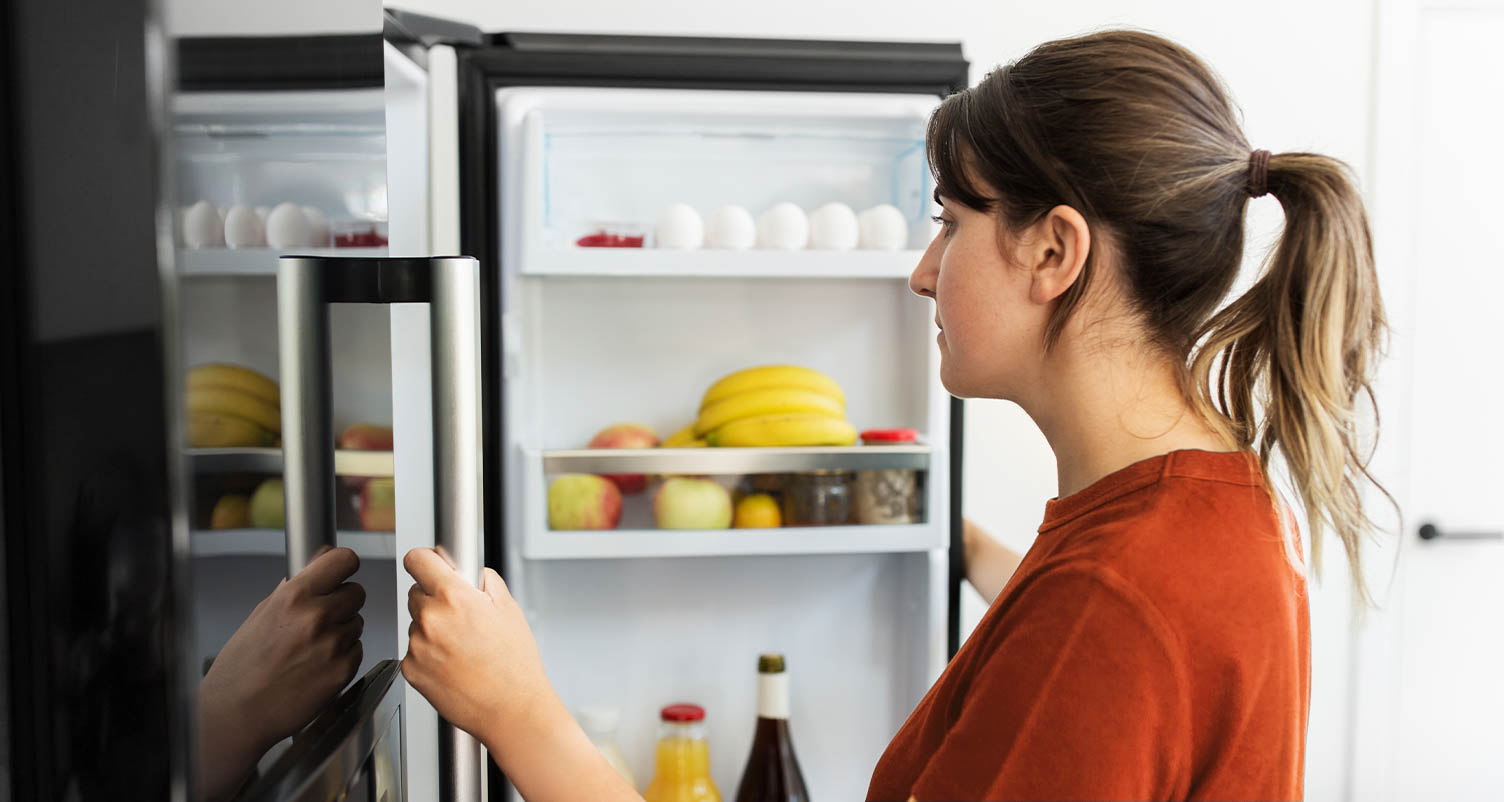 woman opening a fridge full of food and looking at the content