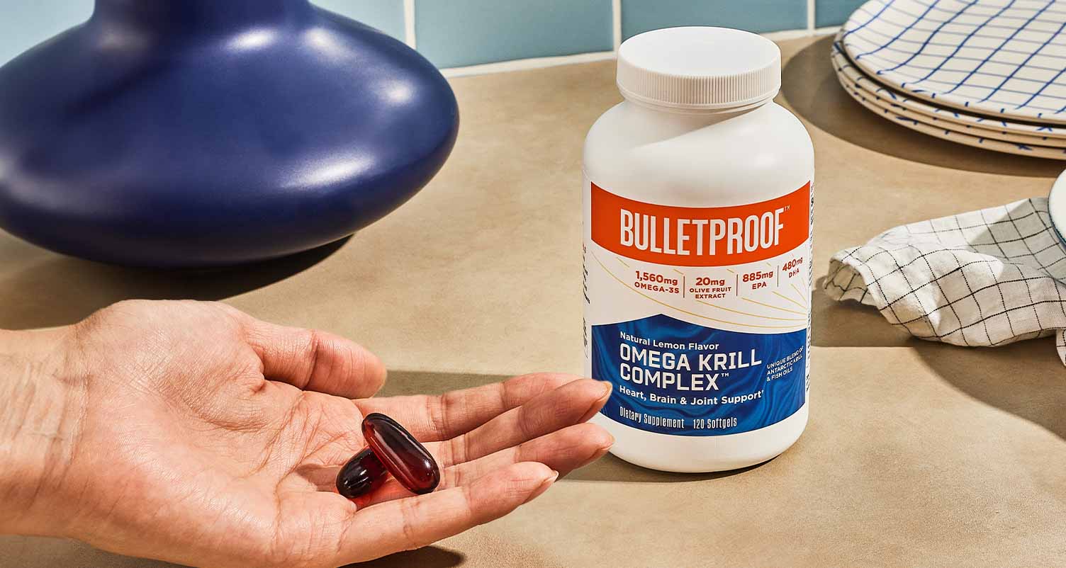 bulletproof omega kirll complex bottle and hand holding supplement pill capsule