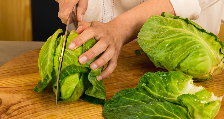 person working with raw cabbage