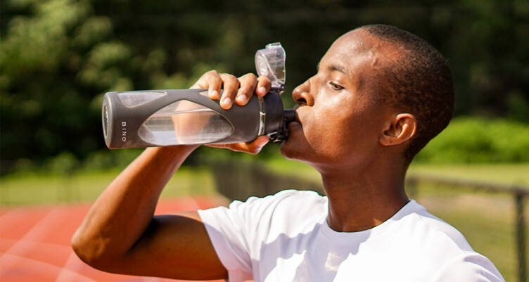 Man drinking water from water bottle on track field