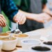 Cups of coffee on a table with the hands of a quality tester checking the coffee with 2 spoons