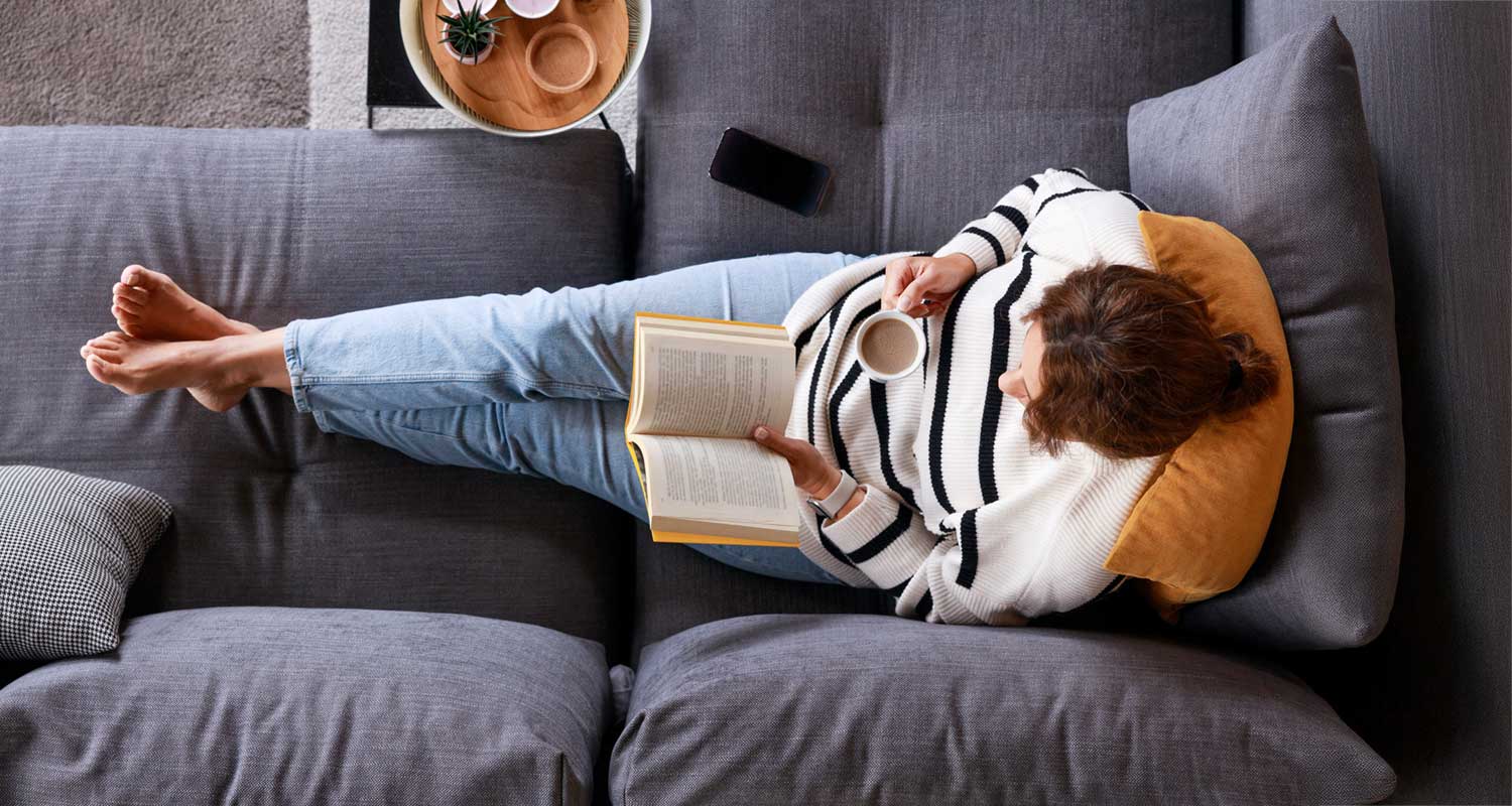woman reading and drinking coffee on the couch