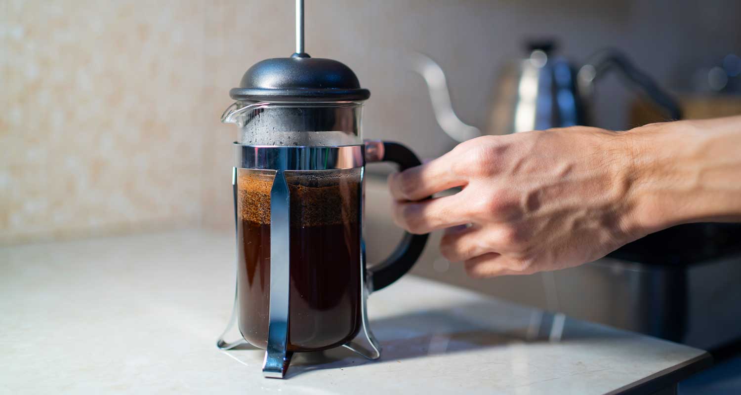 hand holding french press filled with coffee