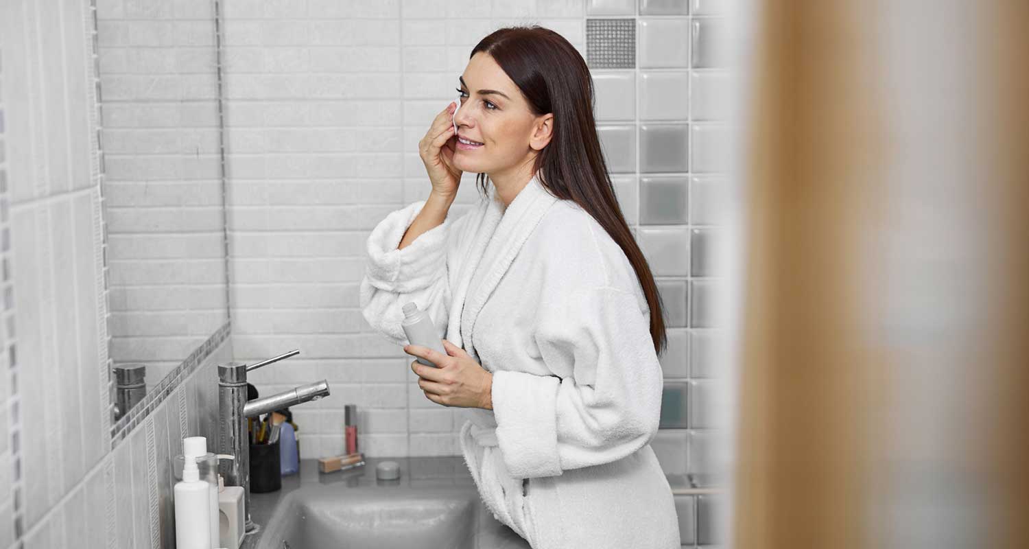 Woman in bathroom applying skincare