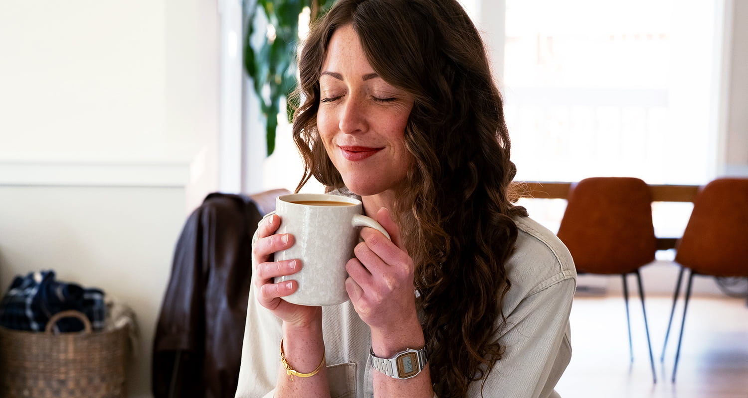 woman smiling into her coffee