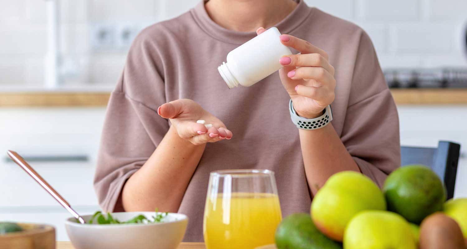 Woman taking supplements while eating