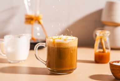 Mug of Bulletproof Sea Salt Hazelnut Mocha sitting in a kitchen setting with it's recipe ingredients in the background.