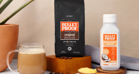 Bulletproof Original Ground Coffee bag, bottle of Brain Octane C8 MCT oil and mug of coffee on kitchen counter with scoop of ghee