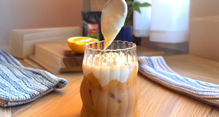 Cold foam dripping into latte on kitchen counter