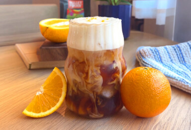 Latte with foam on top aside orange slices