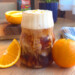 Latte with foam on top aside orange slices