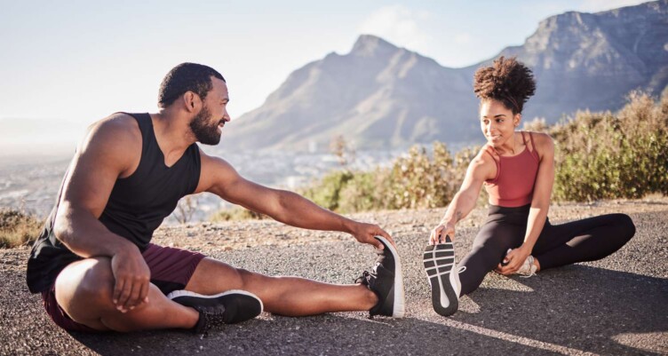 Man and woman stretching on ground before they go for a hike