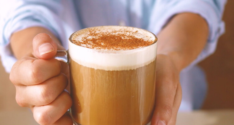 Hand holding latte with cinnamon